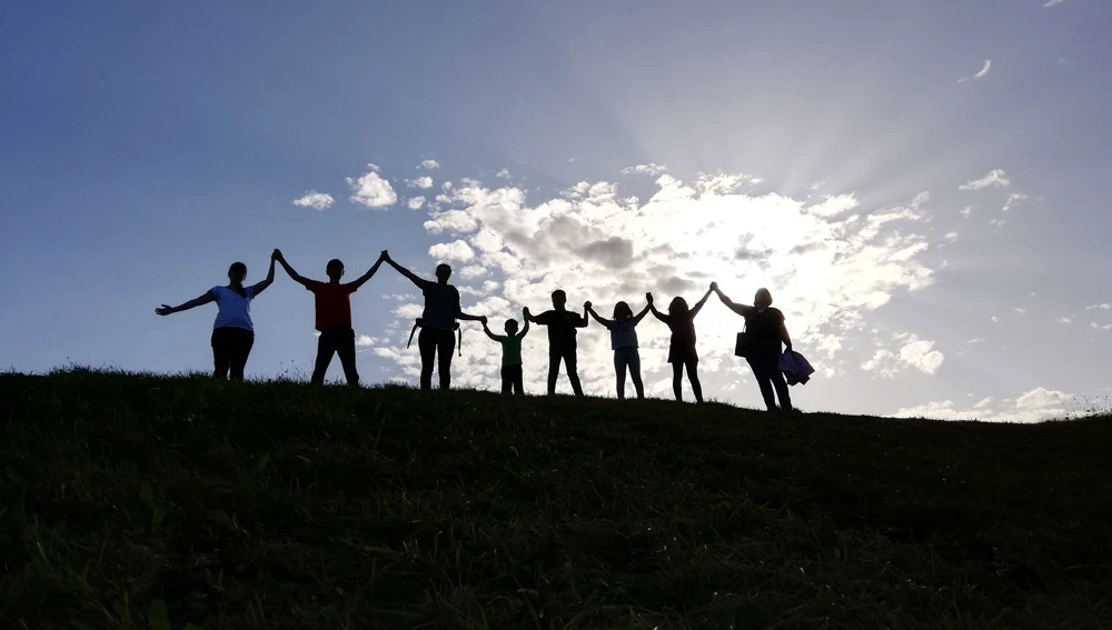 Children and adults are holding hands against the light