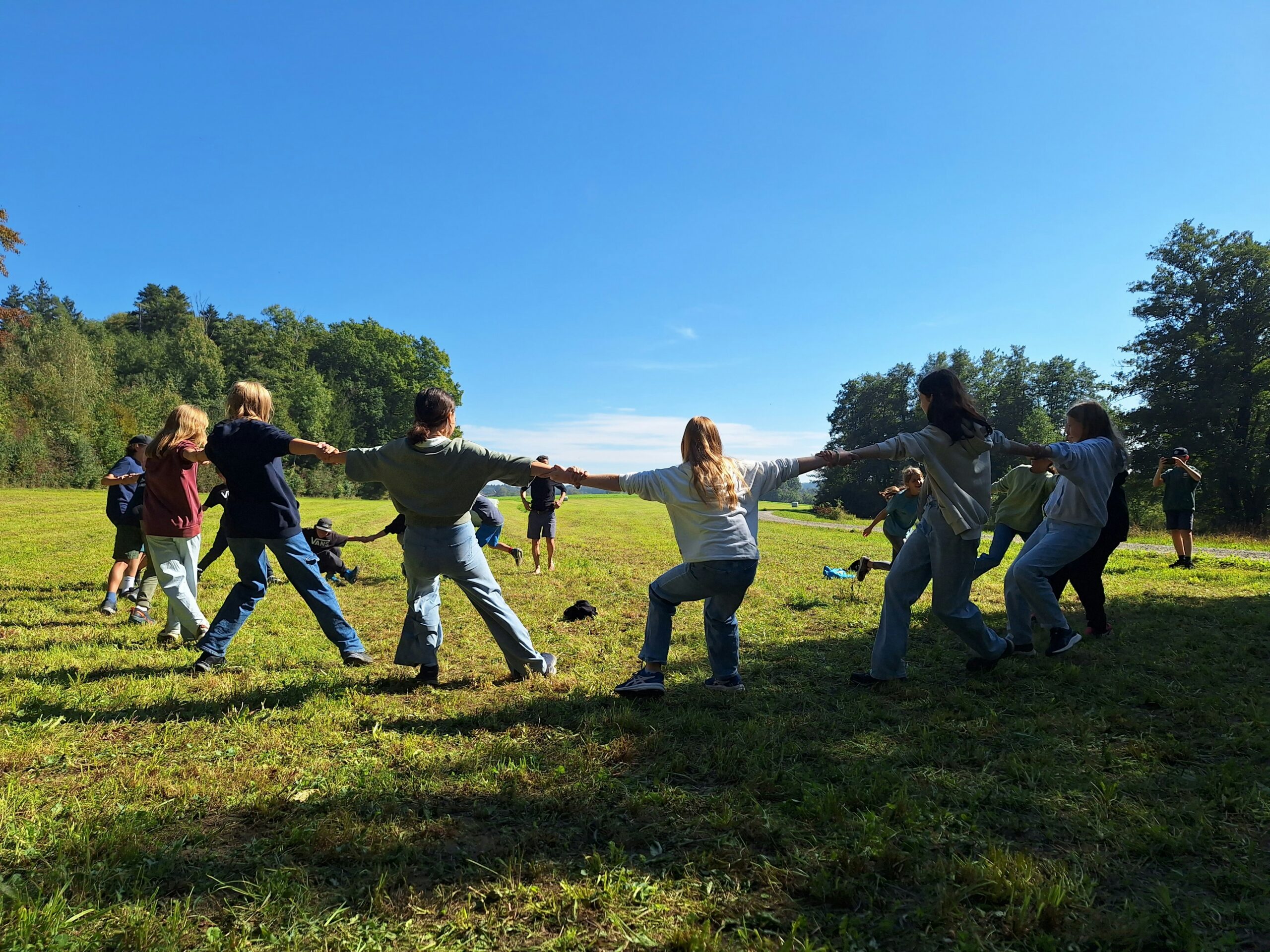 Teenagers are playing on the lawn and holding hands in a circle