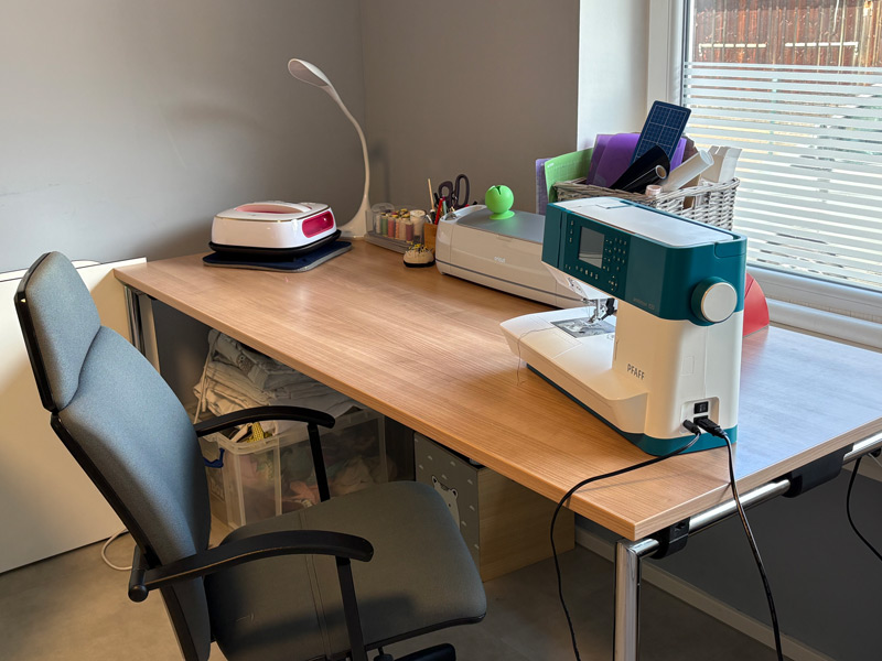Schreibtisch mit Nähmaschine und Stoffen