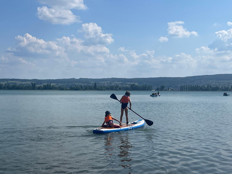 Zwei Kinder auf einem Standup-Paddle auf einem großen See
